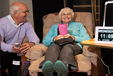 Trying out the furniture in the ‘Living room’ at St Albans & District Older People’s Day