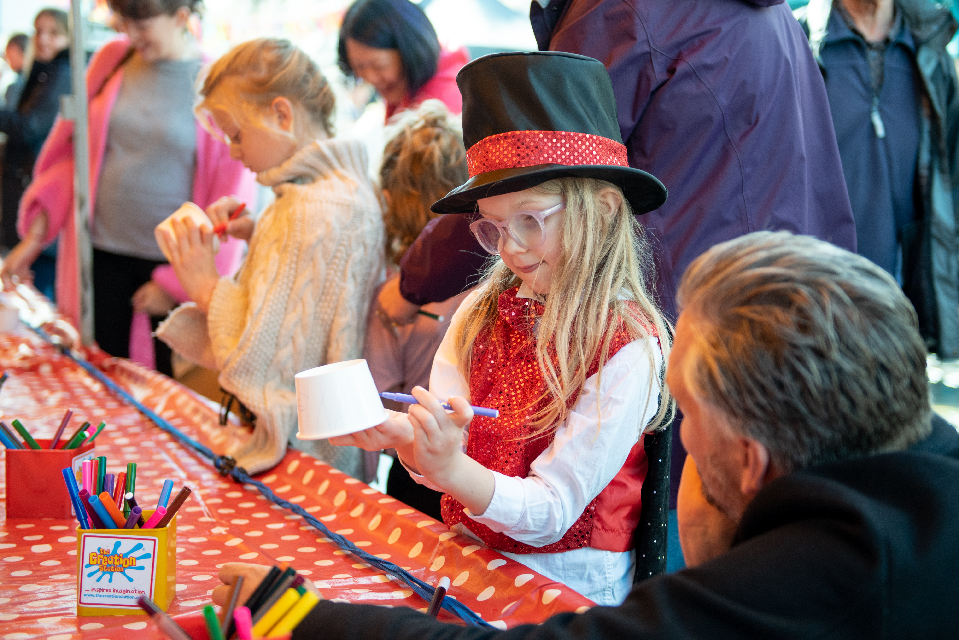 little girl wearing a hat, doing a craft activity