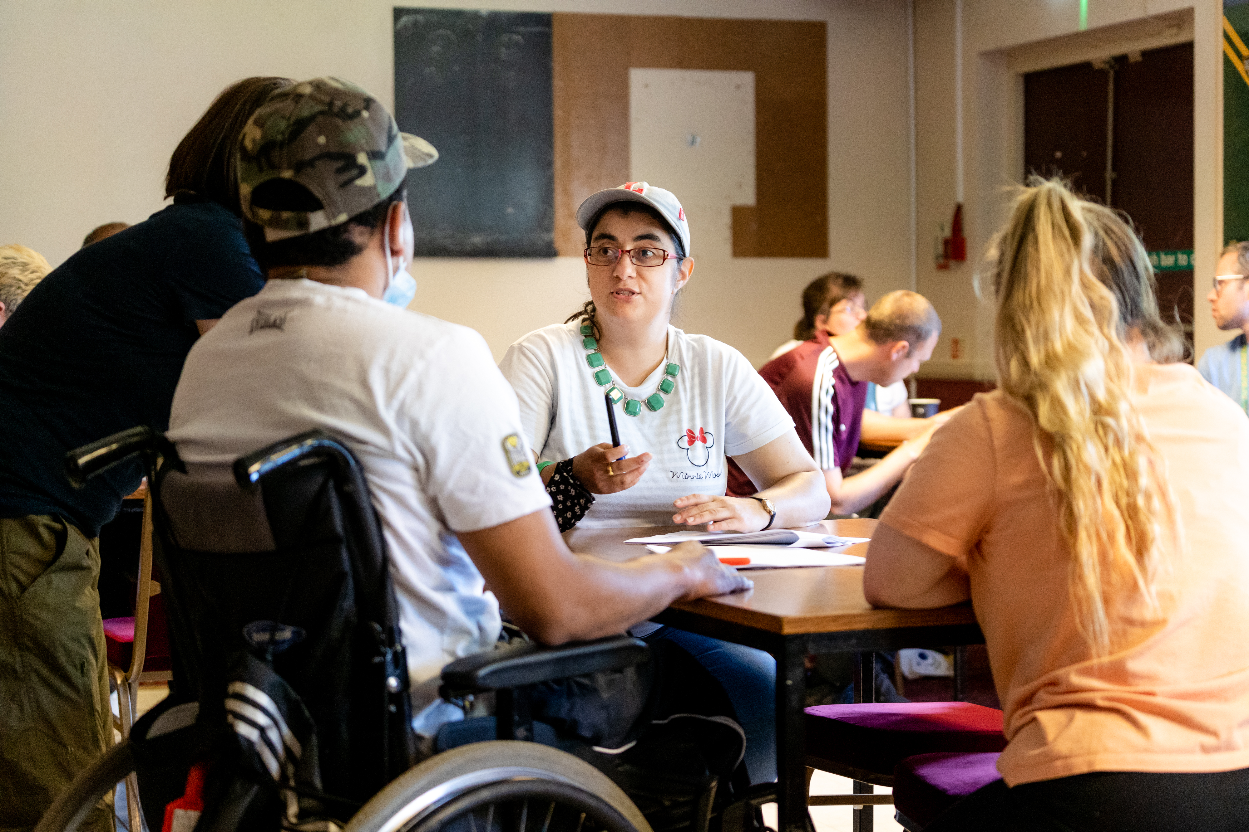 Young adults including wheelchair user in conversation at a table