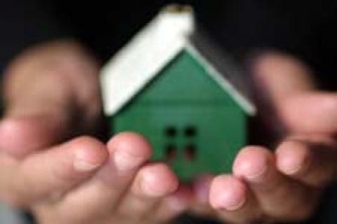 Person holding minature house in their hands